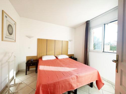 Un dormitorio con una cama con una manta roja. en Appartement 215 supérieur - LES SUITES DE ROBINSON - Résidence avec piscine en bord de Siagne, à Mandelieu-La-Napoule, en Mandelieu-la-Napoule