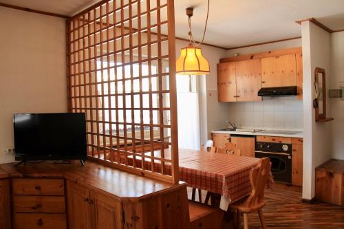 uma cozinha com uma mesa e uma televisão num quarto em Residence Casa Cavalese em Cavalese