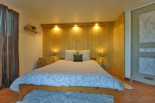 een slaapkamer met een groot bed en een houten muur bij Chambre d'hôtes La Détente - Domaine la Rose des vents in Castelnau-sur-lʼAuvignon