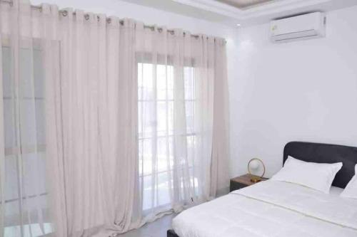 a bedroom with a bed and a window with curtains at Jumeirah on the hills, Mamelles in Dakar