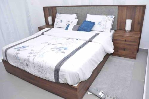 - une chambre dotée d'un grand lit avec des draps blancs et des oreillers bleus dans l'établissement Jumeirah on the hills, Mamelles, à Dakar