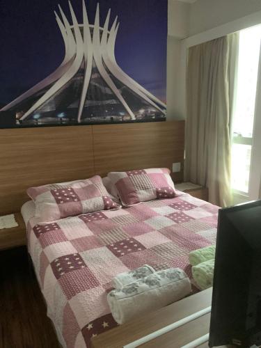 a bedroom with a bed with a checkered blanket at FLAT 1417 in Águas Claras