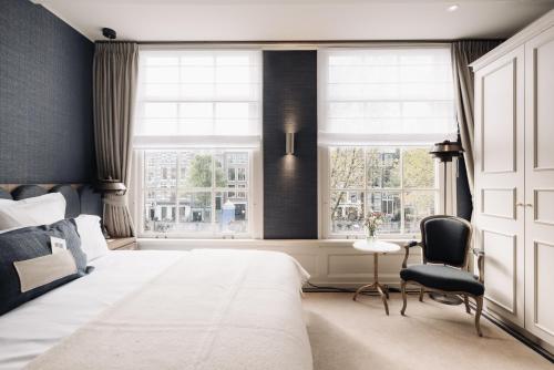 um quarto com uma cama grande e 2 janelas em Hotel 717 em Amsterdã