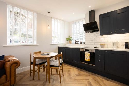 a kitchen with black cabinets and a table with chairs at The Weights and Measures Office in Berwick-Upon-Tweed