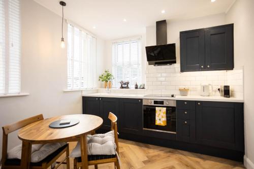 a kitchen with black cabinets and a table and a sink at The Weights and Measures Office in Berwick-Upon-Tweed