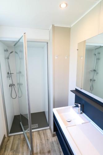 une salle de bain avec une douche, un lavabo et un miroir dans l'établissement CAMPING AZU'RIVAGE, à Azur