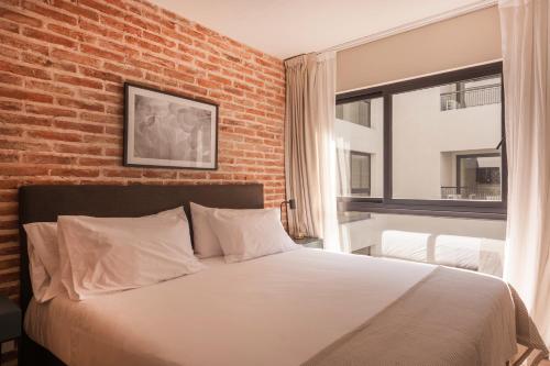 Cama en habitación con pared de ladrillo en Cozy & Modern Luxe Apartment -La Galerie San Telmo- 228 en Buenos Aires