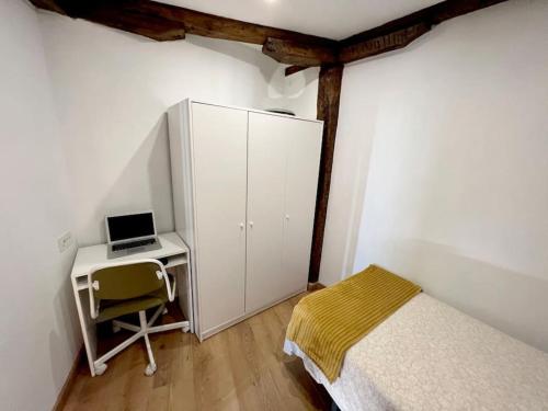 a bedroom with a bed and a desk with a laptop at Portubide Bermeo in Bermeo