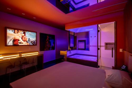 Schlafzimmer mit einem Bett, einem TV und einer Badewanne in der Unterkunft Motel Belle (Adult Only) in São Paulo