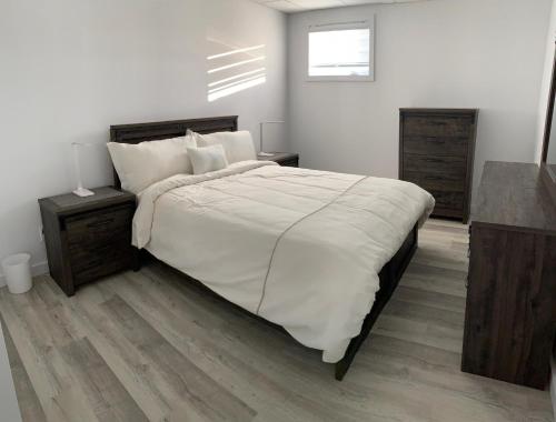 um quarto com uma cama grande e lençóis brancos em Chalets domaine Otis em Saint-Félix-d'Otis