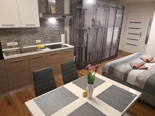 a kitchen with two beds and a table with flowers on it at Honey Apartment Lendava in Lendava