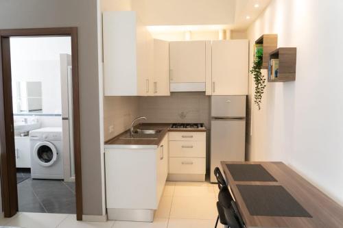 a kitchen with white cabinets and a sink and a table at B&B Intero Appartamento Forum e Metro Milanofiori in Assago