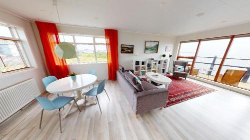 a living room with a table and chairs and a couch at Gotuhus - Sea View Apartment in Hellissandur