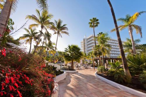 einen Gehweg mit Palmen und einem Gebäude in der Unterkunft Hotel Gran Canaria Princess - Adults Only in Playa del Ingles