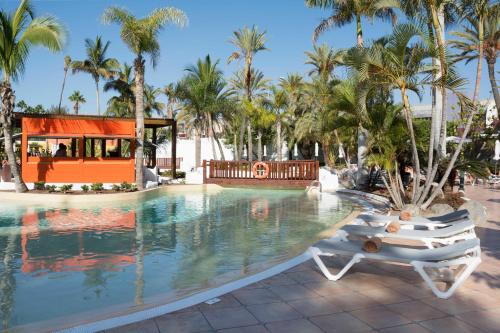 una piscina presso il resort con due sedie a sdraio e palme di Hotel Gran Canaria Princess - Adults Only a Playa del Ingles