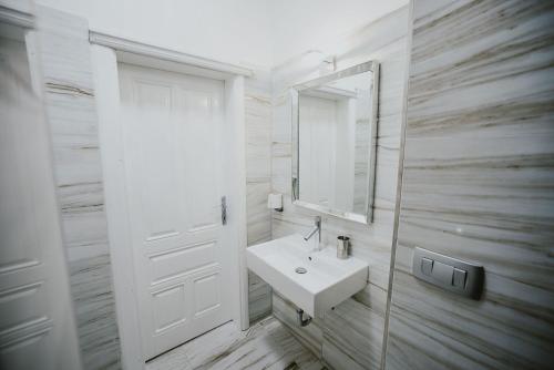 a white bathroom with a sink and a mirror at Kenti Residence in Ljubljana