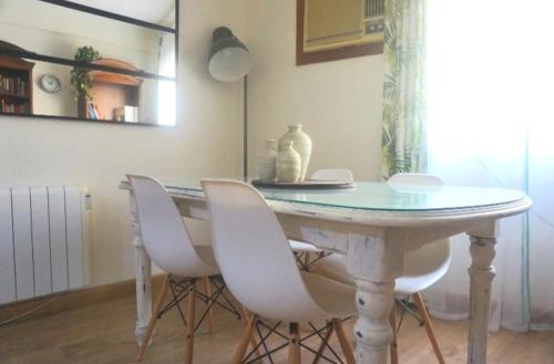 セビリアにあるRomantic apartment with free parkingのダイニングルームテーブル(白い椅子、花瓶付)