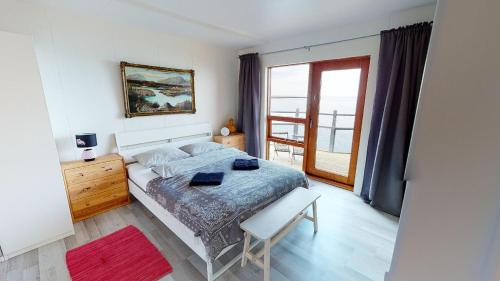 a bedroom with a bed and a large window at Brenna: Cliffside Apartment in Hellissandur