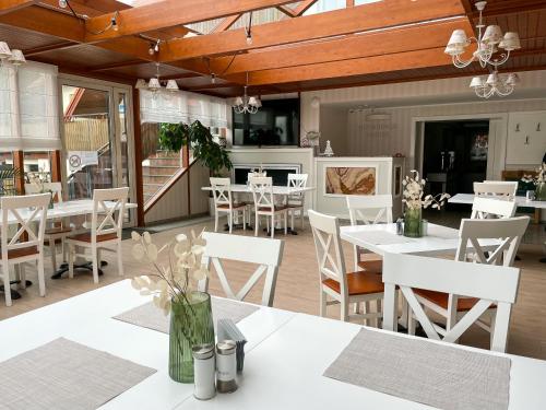un comedor con mesas blancas y sillas blancas en Marina Śniardwy Resort, en Nowe Guty