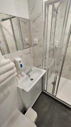 La salle de bains blanche est pourvue d'une douche et d'un lavabo. dans l'établissement Fasthotel Well Inn Mâcon sud - un hôtel FH Confort, à Charnay-lès-Mâcon