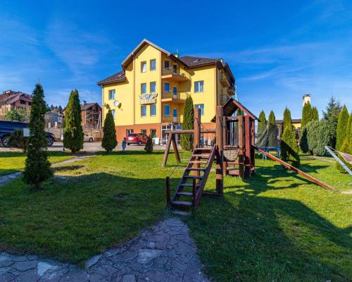 a playground in front of a yellow building at Вілла ЮРАН Східниця in Skhidnitsa