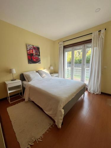a bedroom with a large bed and a large window at Casa Praia Ofir in Esposende