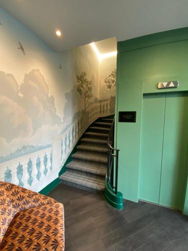 a staircase in a building with a painting on the wall at Hôtel Marguerite in Orléans