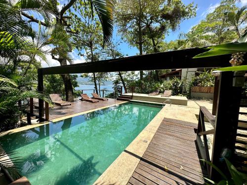 a swimming pool in a yard with a wooden deck at Casas Do Mar in Ilhabela