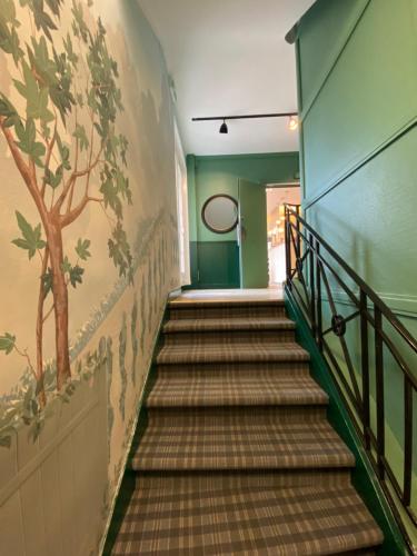 a staircase in a building with a painting on the wall at Logis Hôtel Marguerite in Orléans