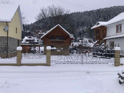 a fence in front of a house in the snow at Yablunevyi Tsvit in Yaremche