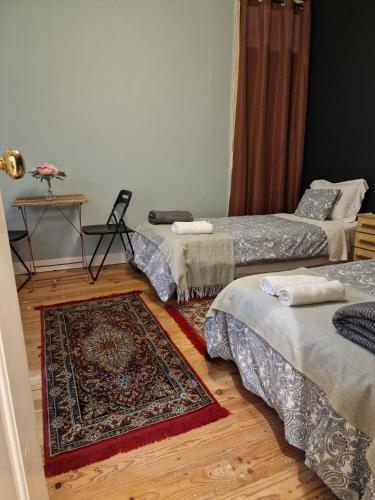 a room with three beds and a rug on a wooden floor at D&N Hospedagem Lisboa in Lisbon