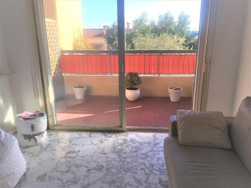 ein Wohnzimmer mit einem Sofa und einer Glasschiebetür in der Unterkunft Appartement de 1 à 6 personnes Beaulieu sur mer, climatisé, proche Nice et Monaco tout confort 2 chambres in Beaulieu-sur-Mer