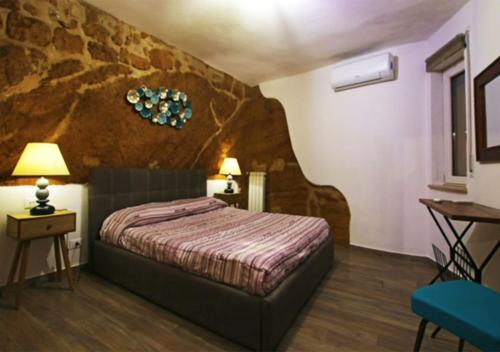 a bedroom with a bed and a rock wall at Rabatè in Agrigento