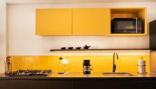 a kitchen with a sink and a stove and yellow cabinets at Topá House in Medellín