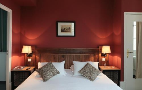 a bedroom with red walls and a bed with two tables at Domaine de Saulon in Saulon-la-Rue