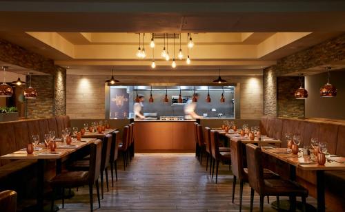 a restaurant with wooden tables and chairs and a counter at Coldra Court Hotel by Celtic Manor in Newport