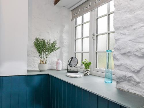 a bathroom with a blue counter and a window at Moohey Barn in Liskeard