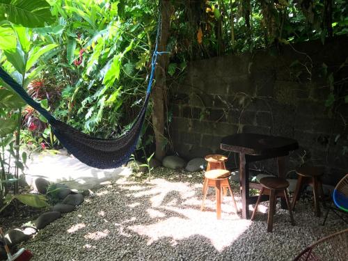 a hammock in a garden with a table and stools at FLOR DE PARAISO BUNGALOWS in Montezuma