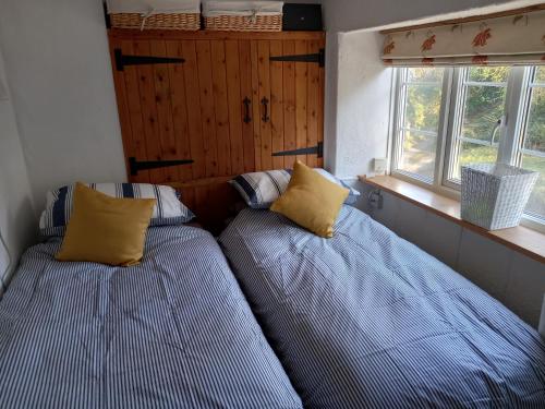 two beds in a small room with two windows at Laurel cottage Melplash in Netherbury