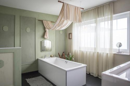 a bathroom with a tub and a large window at Alte Flachsfarm in Cottbus