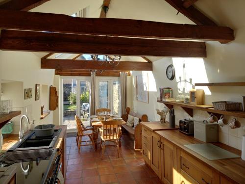 a kitchen with a table and a dining room at Laurel cottage Melplash in Netherbury