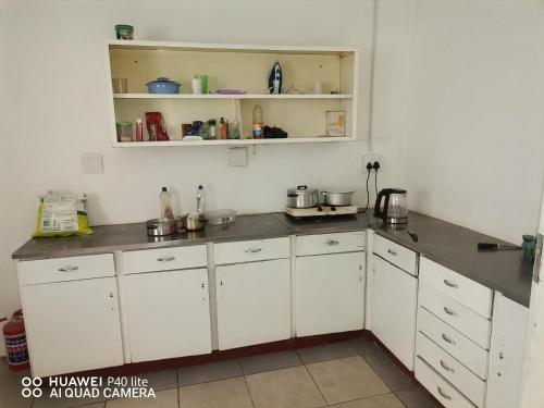 a kitchen with white cabinets and gray counter tops at Sunset Executive Lodge in Boksburg