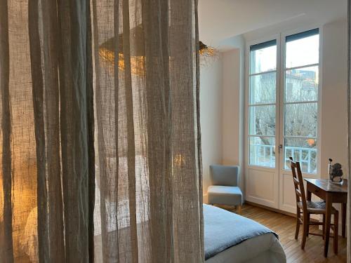 a bedroom with a bed and a table and a window at Luxe et Charme - Le Carré Saint-Silain - Meublé de tourisme 3 étoiles in Périgueux
