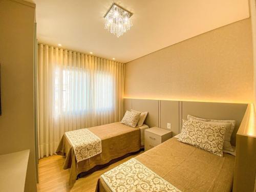a bedroom with two beds and a chandelier at Rosa Edifício Vivere Canela in Canela