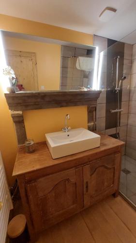 une salle de bain avec un lavabo blanc sur un comptoir en bois dans l'établissement Chez Maritou, à Besse-et-Saint-Anastaise