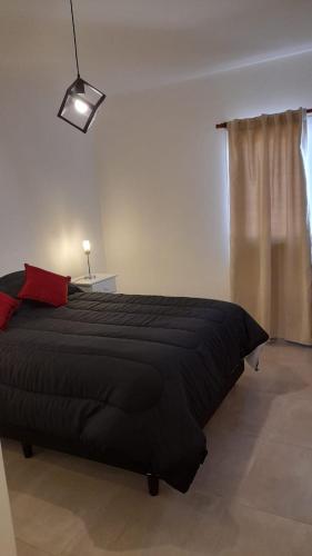 1 dormitorio con cama negra y almohada roja en Bello Departamento en Gran Mendoza en Godoy Cruz