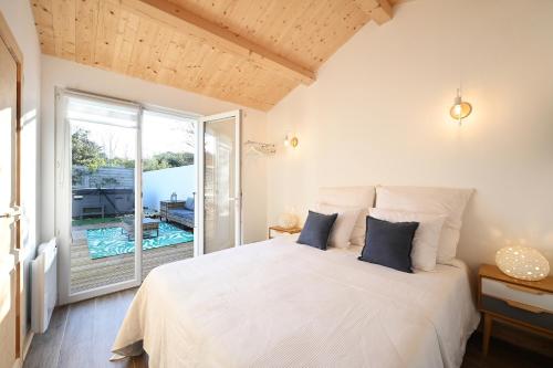 une chambre avec un lit blanc et une grande fenêtre dans l'établissement MAISONS DE VACANCES LES RÉTHAISES, à La Couarde-sur-Mer