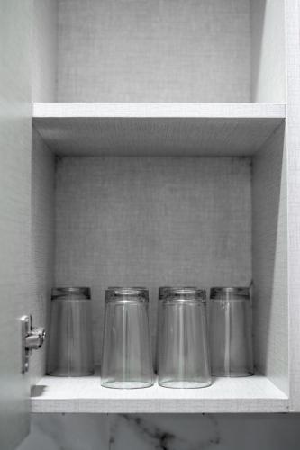 four glass jars sitting on a shelf in a kitchen at The Lodgers 1 BHK Serviced Apartment Golf Course Road Gurgaon in Gurgaon