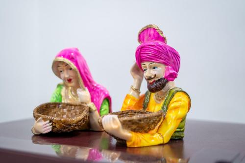 two dolls sitting on a table playing with a basket at The Lodgers 1 BHK Serviced Apartment Golf Course Road Gurgaon in Gurgaon
