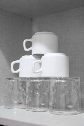 a group of cups and glasses sitting on a shelf at The Lodgers 1 BHK Serviced Apartment Golf Course Road Gurgaon in Gurgaon